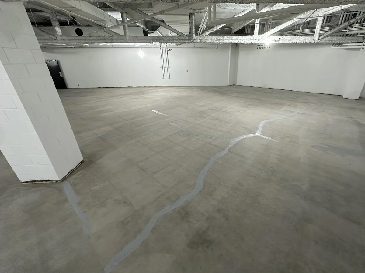 Large commercial space with bare concrete and marked cracks before coating