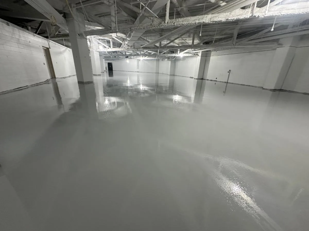Gray epoxy floor coating in a large commercial building with steel joists
