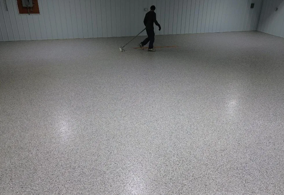 Crew rolling topcoat on a flake floor in a steel sided pole shop