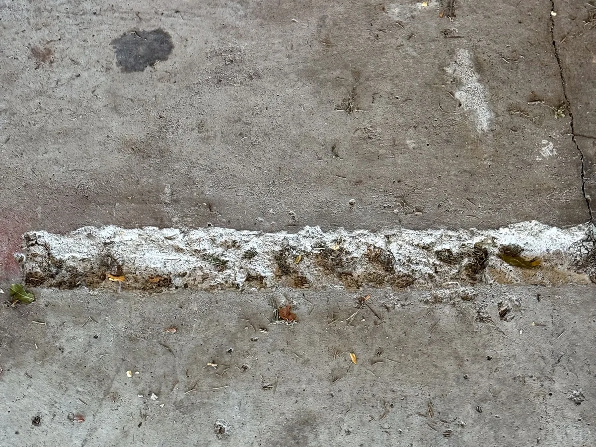 Spalled and broken edges along a control joint in a concrete slab