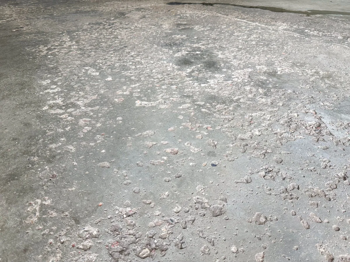 Heavily pitted and spalled concrete garage slab before repair