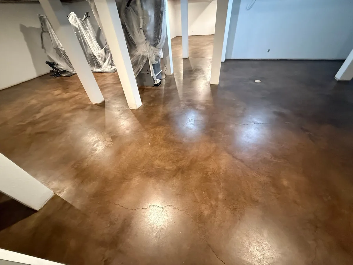 Mottled brown stained concrete basement floor with a glossy clear finish
