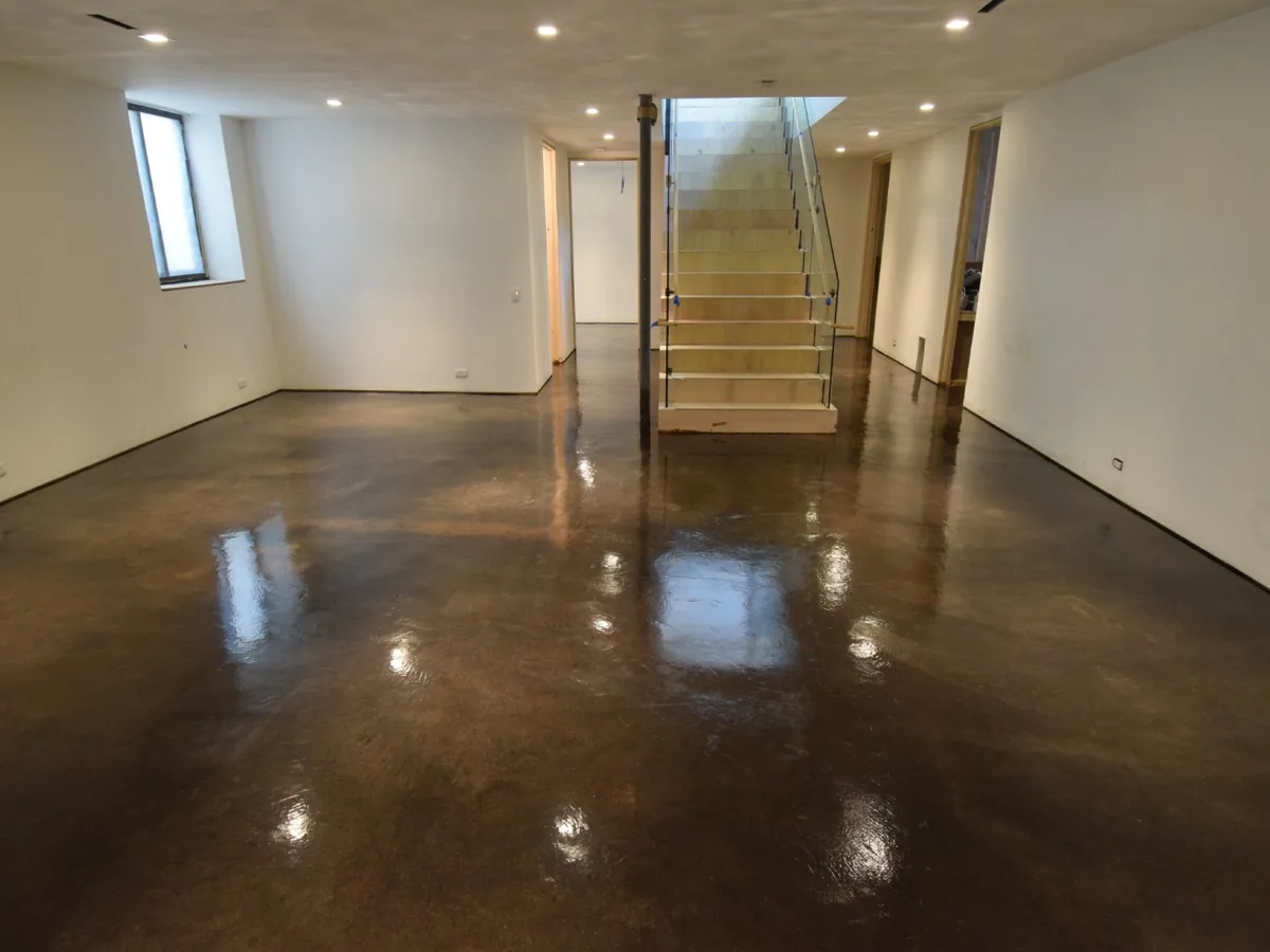 Dark brown acid stained concrete floor in a finished basement