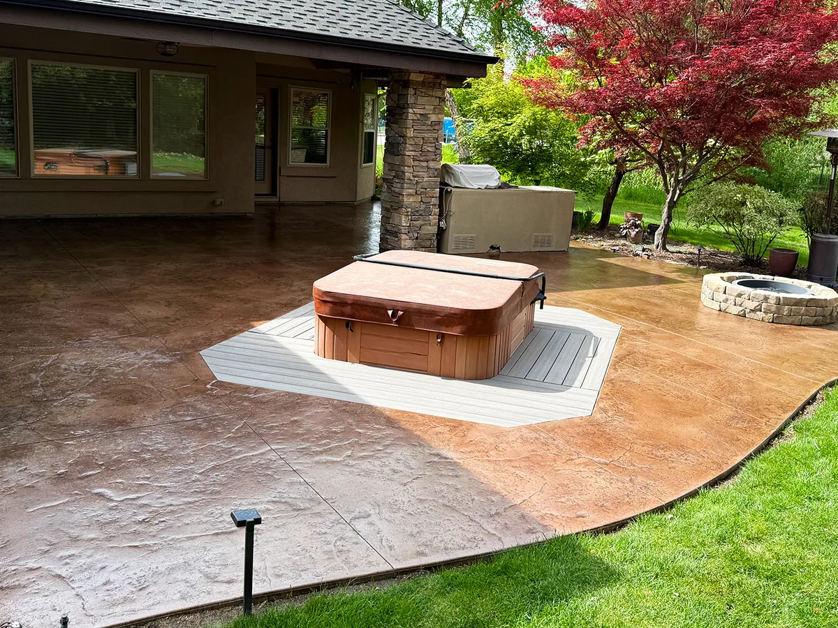 Stained and sealed stamped concrete patio with a hot tub and fire pit