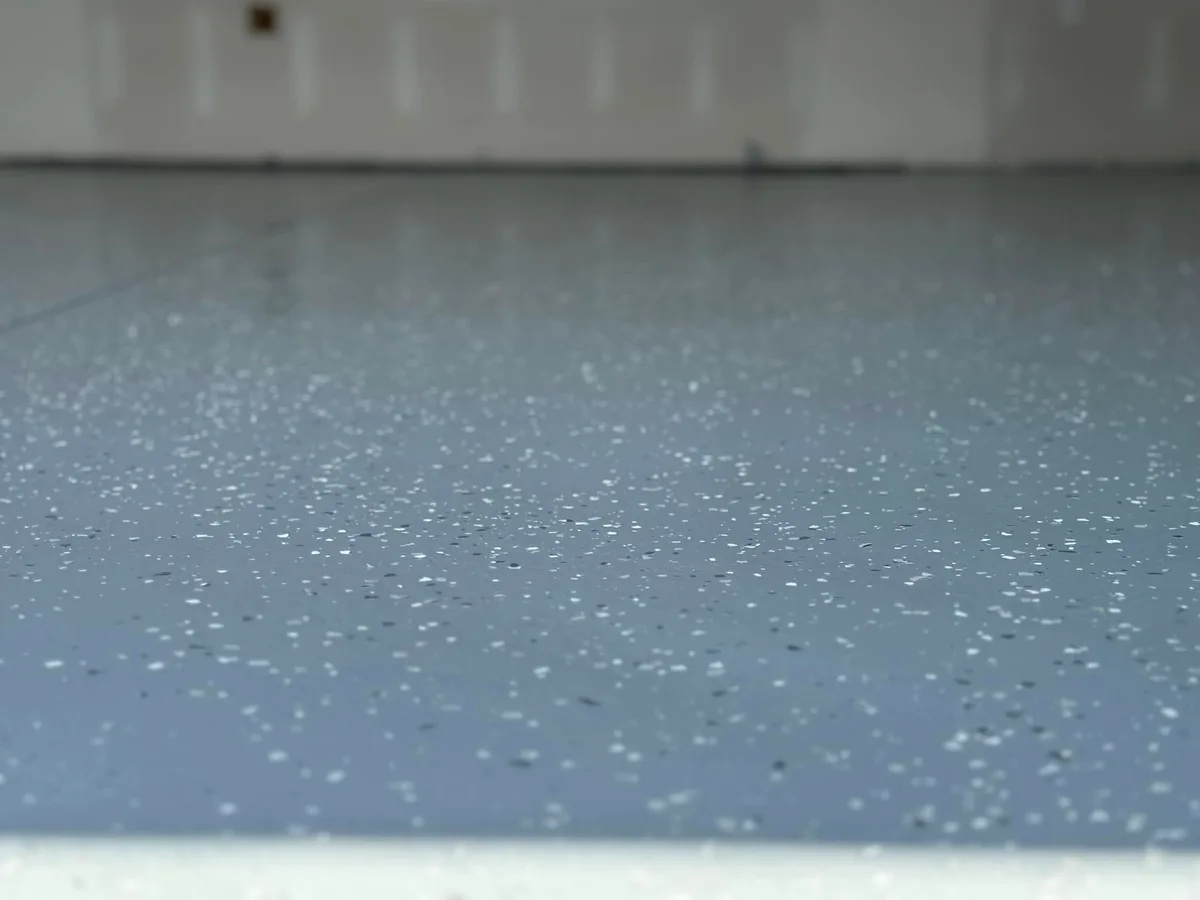 Close up of a gray epoxy floor with light decorative flake