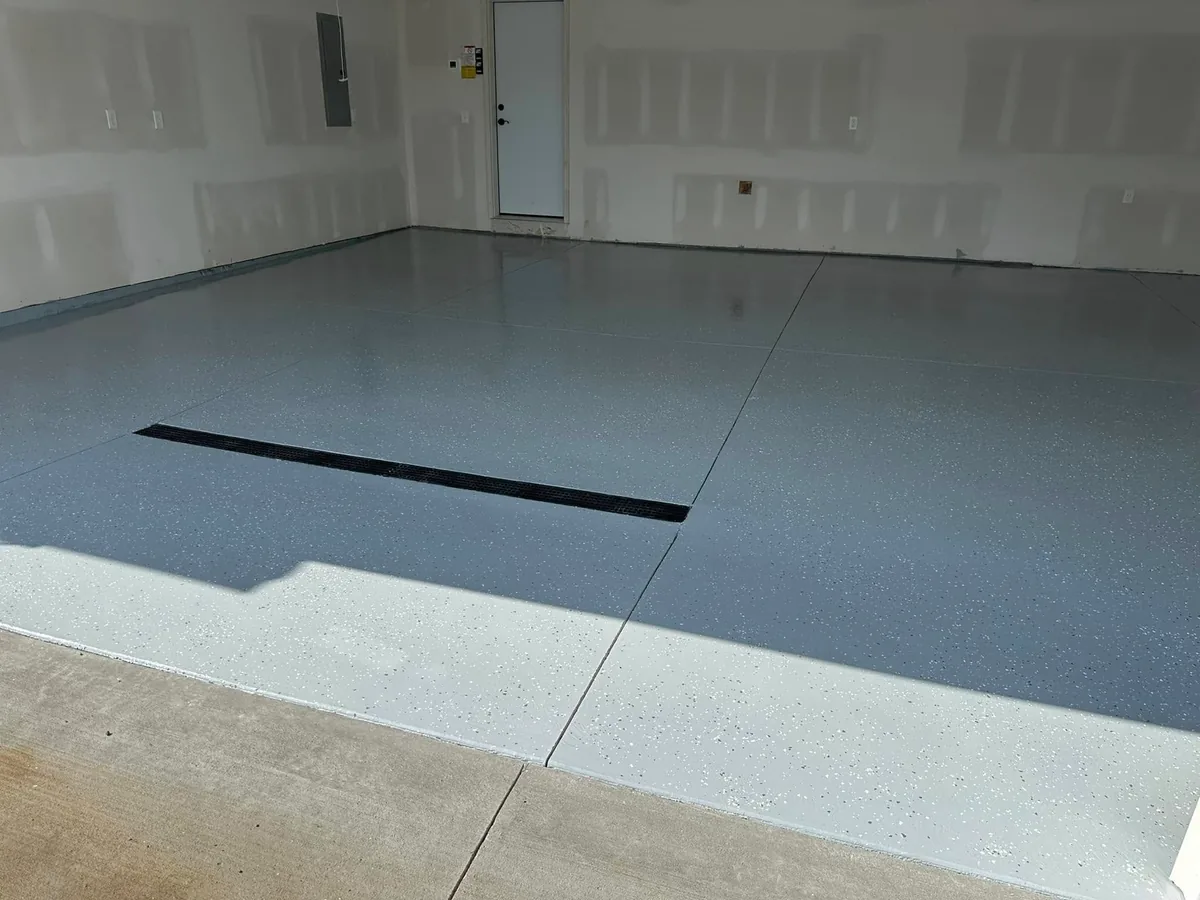 Solid gray epoxy garage floor coating with light decorative flake and a trench drain