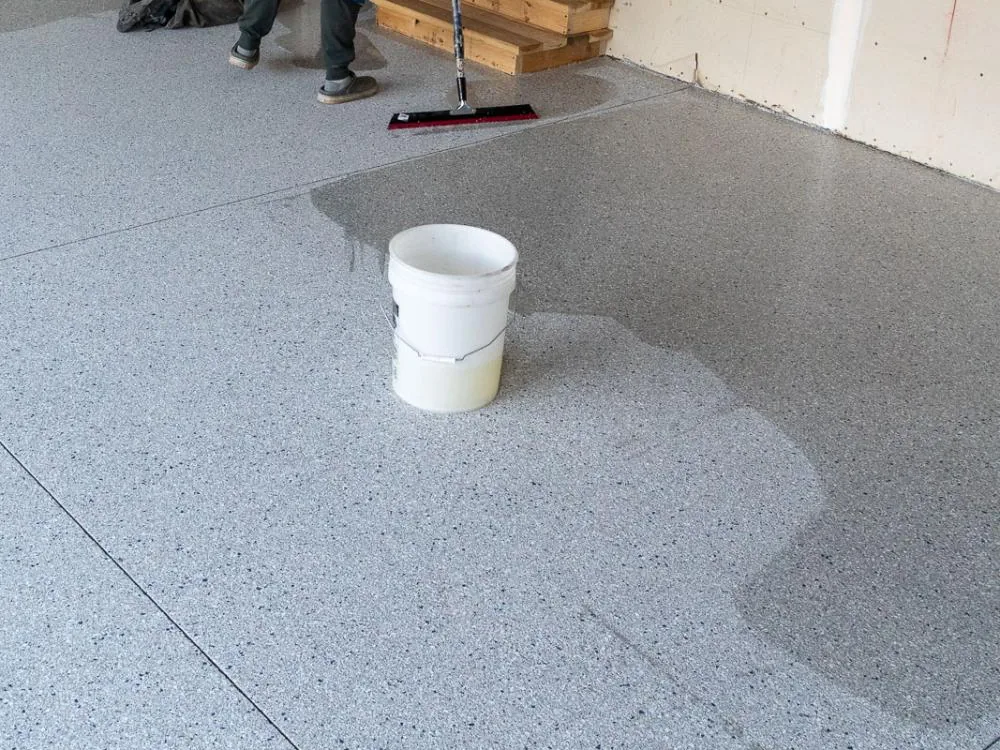Crew spreading clear topcoat over a flake floor with a squeegee