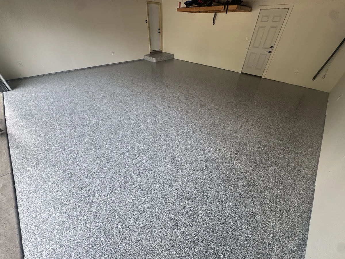 Finished gray flake garage floor with a white entry door