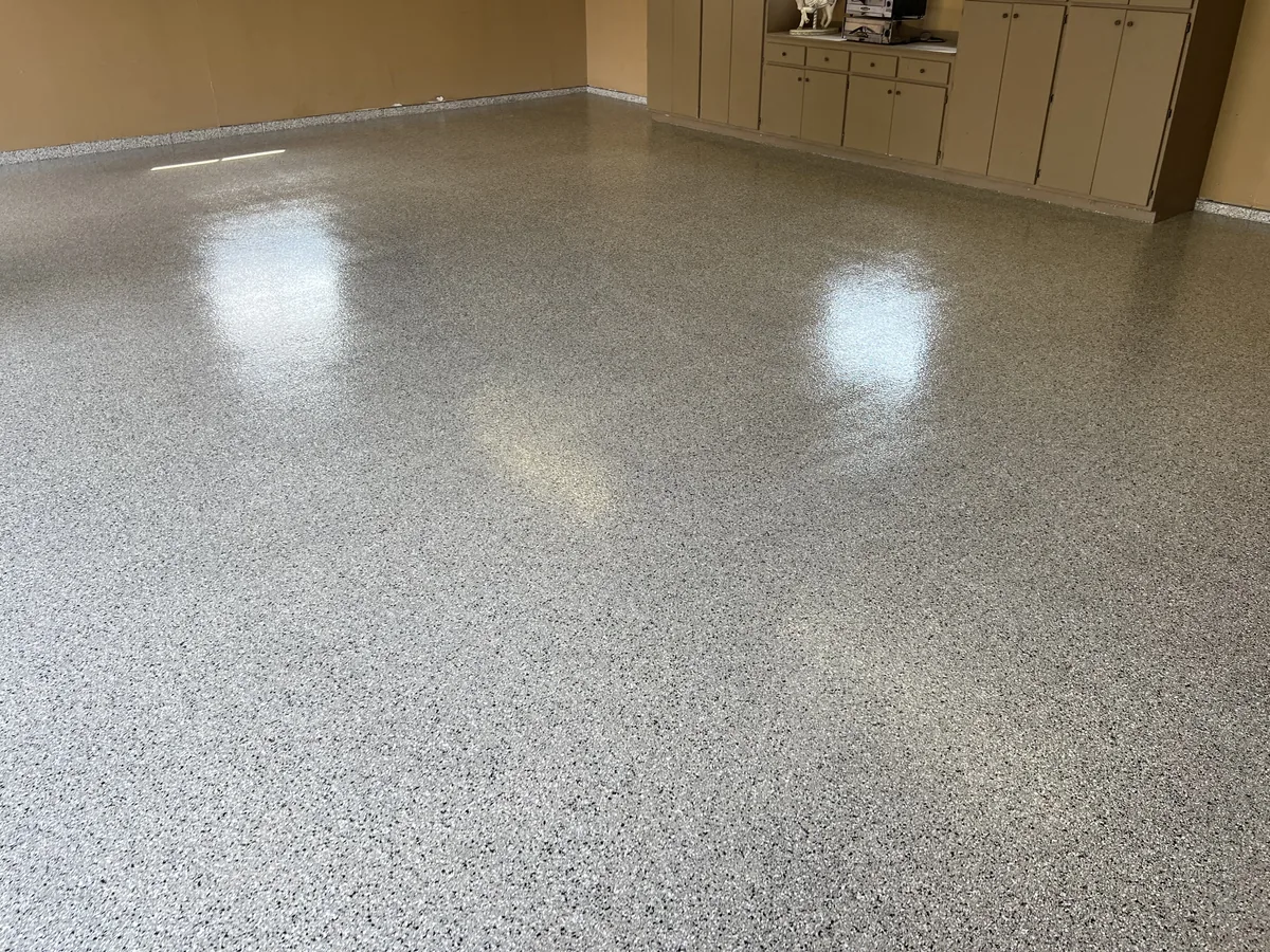 High gloss gray flake garage floor beside built in cabinets