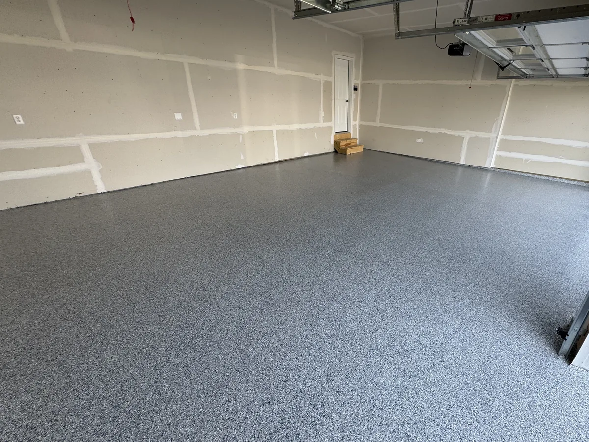 Gray flake floor coating in a newly built garage with taped drywall