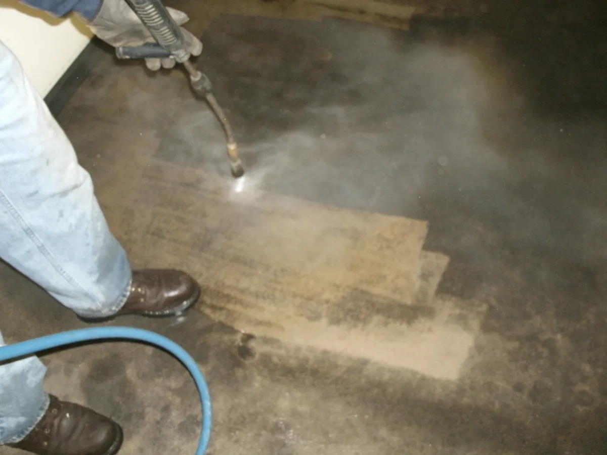 Pressure washer wand cleaning a dirty concrete garage floor
