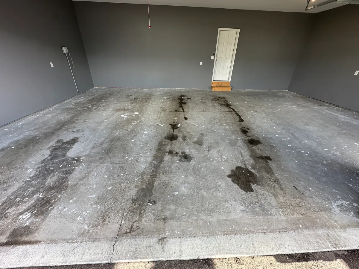 Bare garage slab with tire tracks, salt stains and grime before cleaning