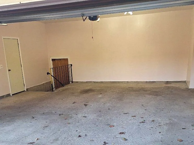 Bare stained concrete garage floor with leaves before coating