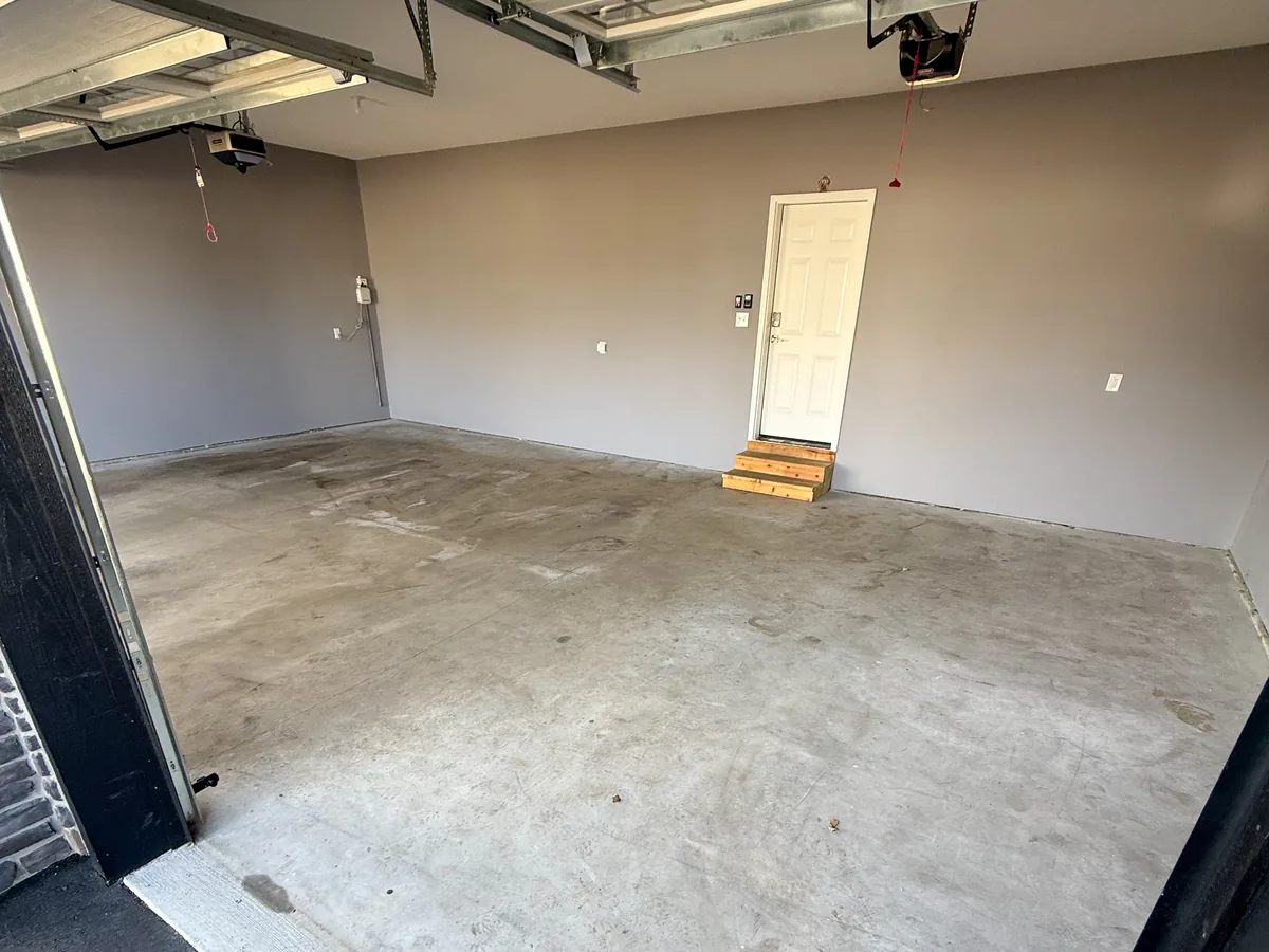 Bare concrete garage floor with tire marks and stains before coating