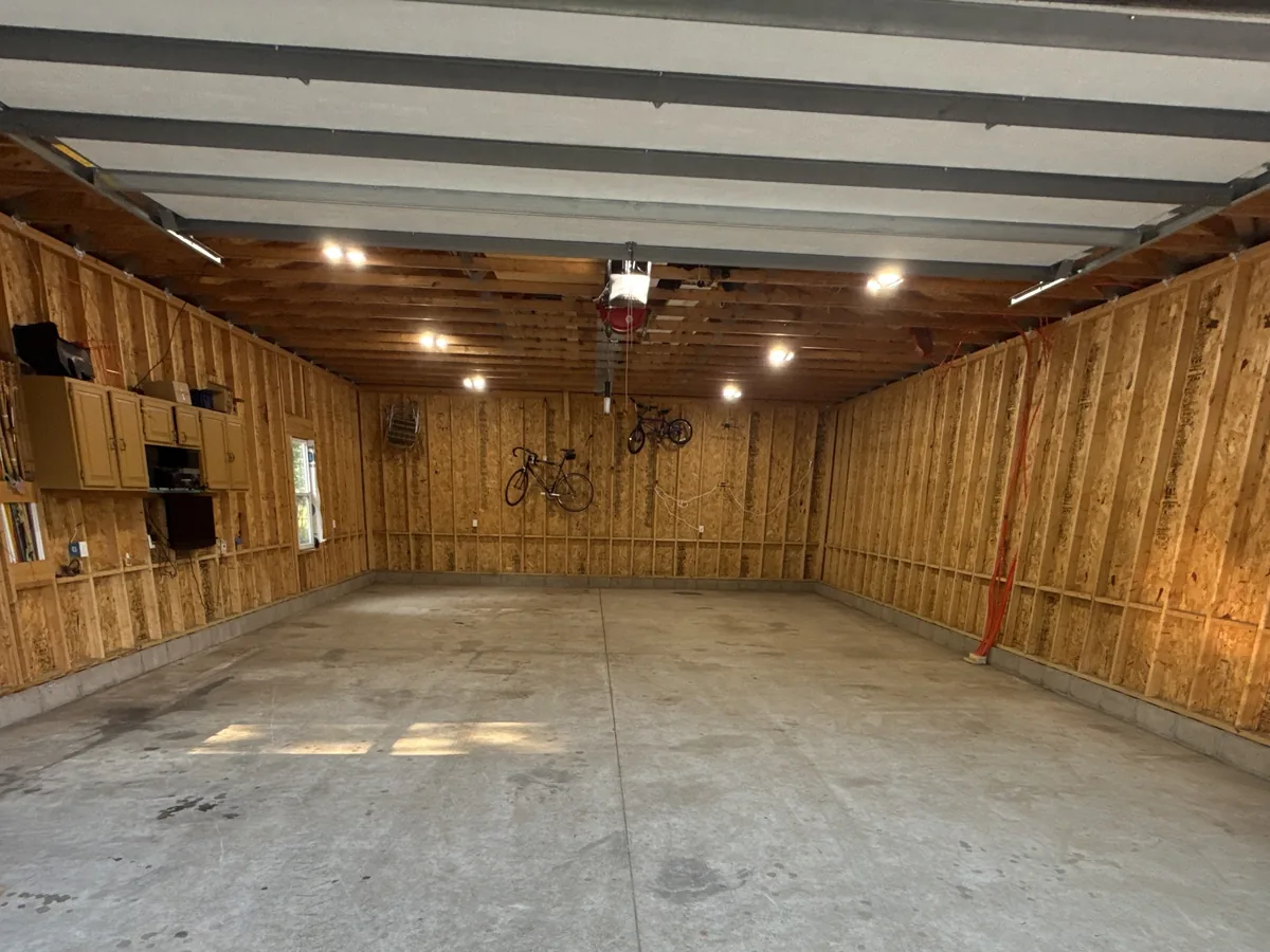 Large garage with wood walls and a bare stained concrete floor