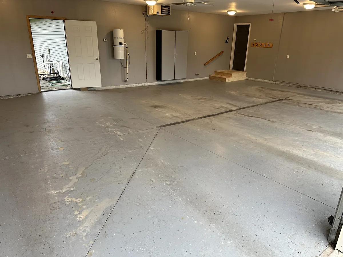 Worn and stained concrete floor in a large garage before coating