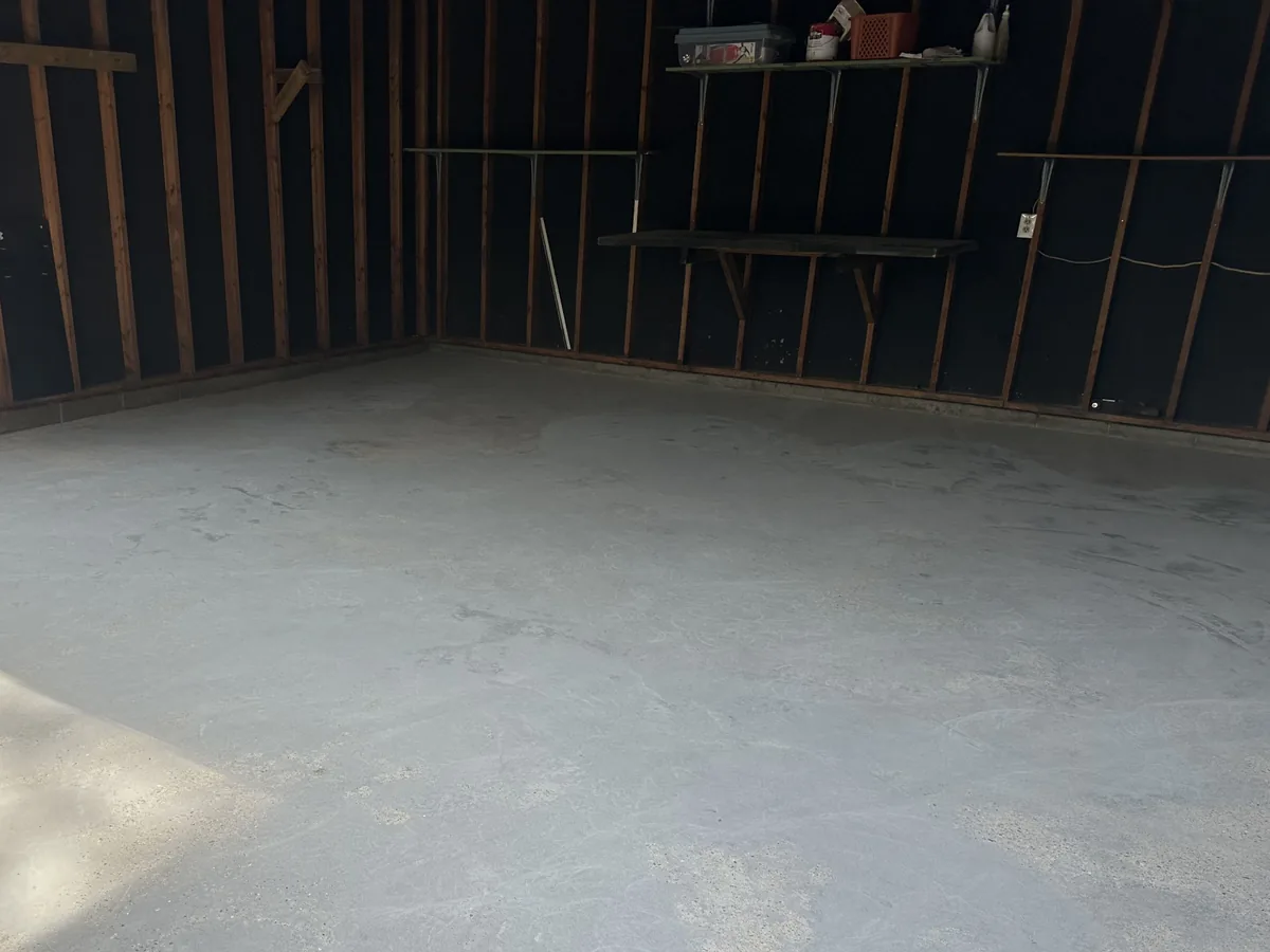 Bare concrete slab in a garage with black painted stud walls