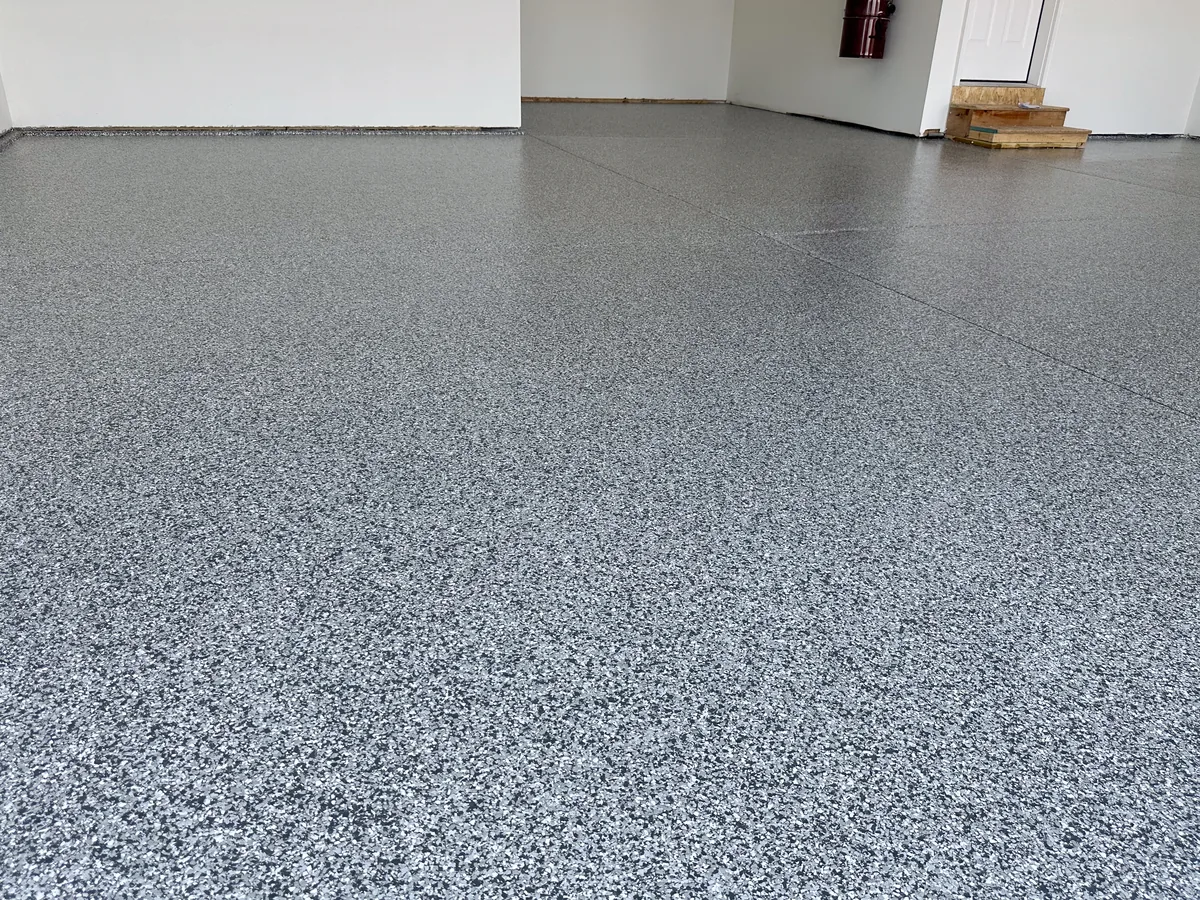 Low angle view of a finished gray flake garage floor with a white entry door
