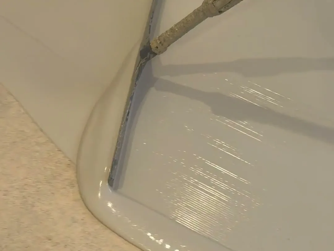 Squeegee spreading a gray base coat over ground concrete