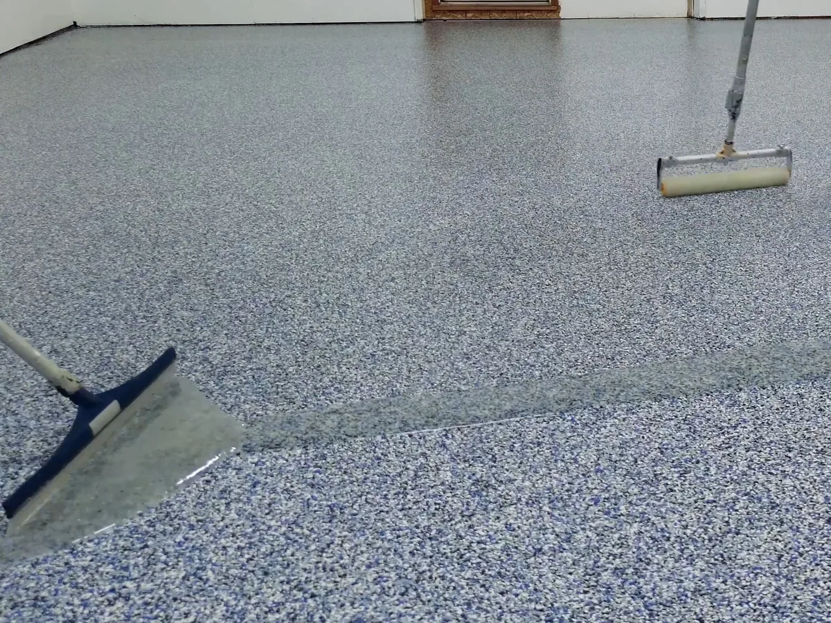Clear topcoat going on over a flake floor with a squeegee and a roller