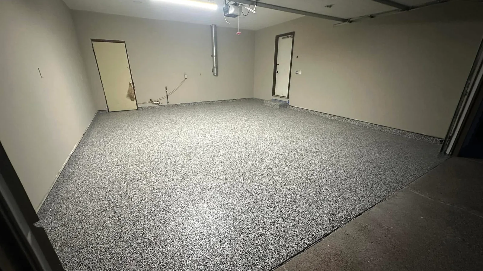 Gray flake garage floor coating lit by a ceiling shop light