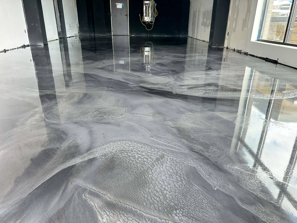 Glossy gray metallic epoxy floor with window reflections
