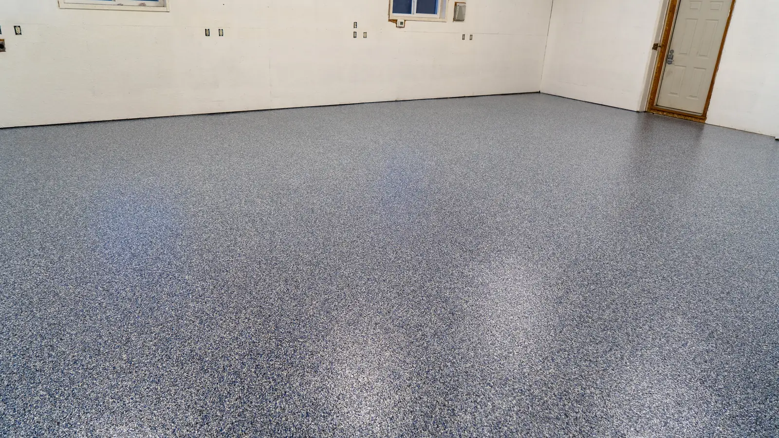 Finished blue and gray flake garage floor coating in a garage with white walls