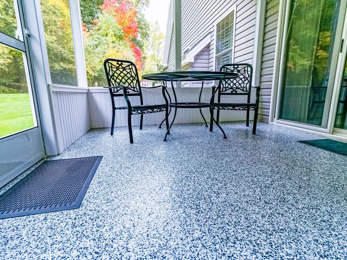 Blue and white flake floor coating on a screened porch with a bistro table