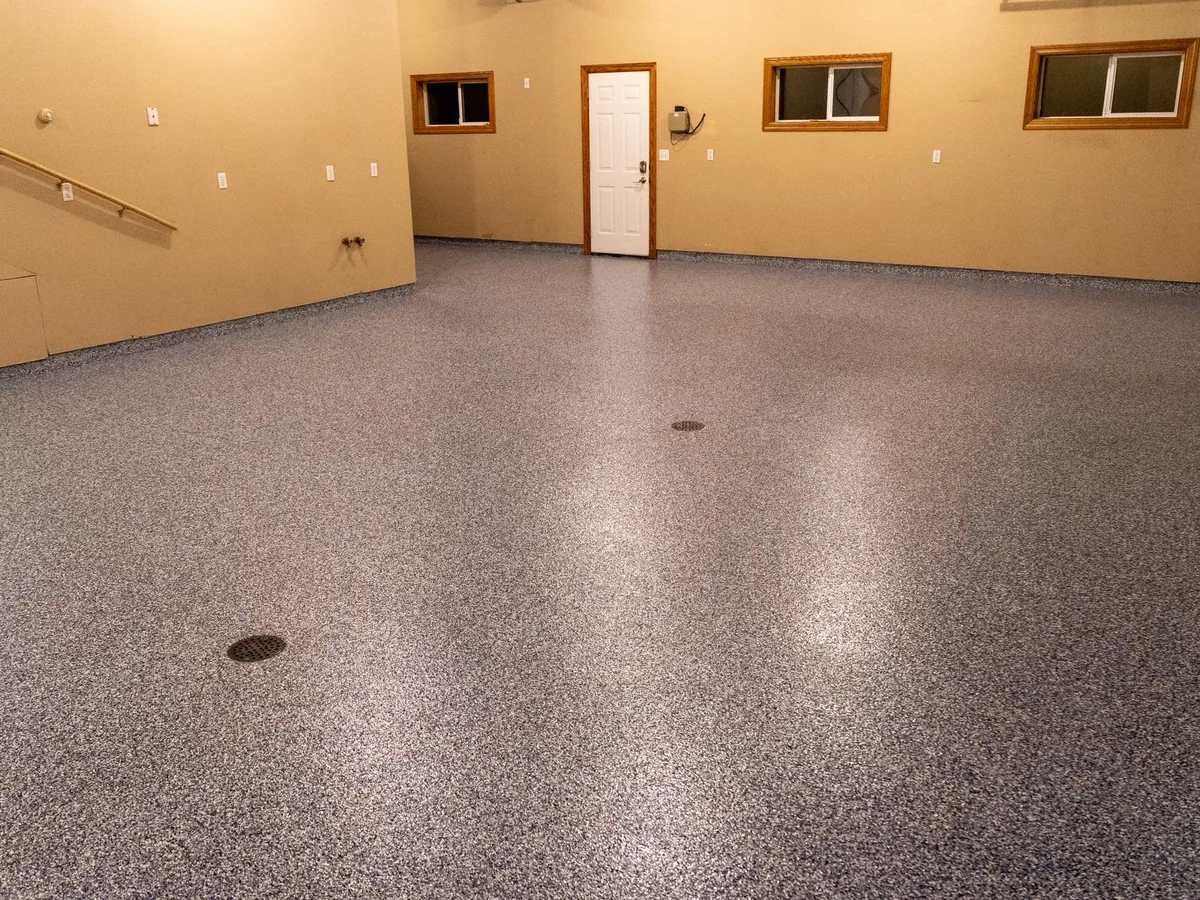 High gloss topcoat on a flake floor in a large tan walled garage