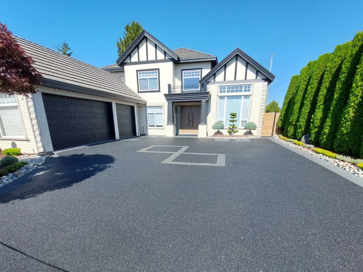 Charcoal rubber paving surface on a residential driveway with light gray border inlays