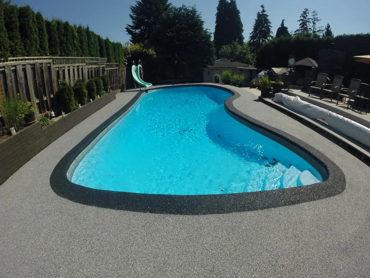 Gray rubber pool deck resurfacing with a dark rubber band at the pool edge