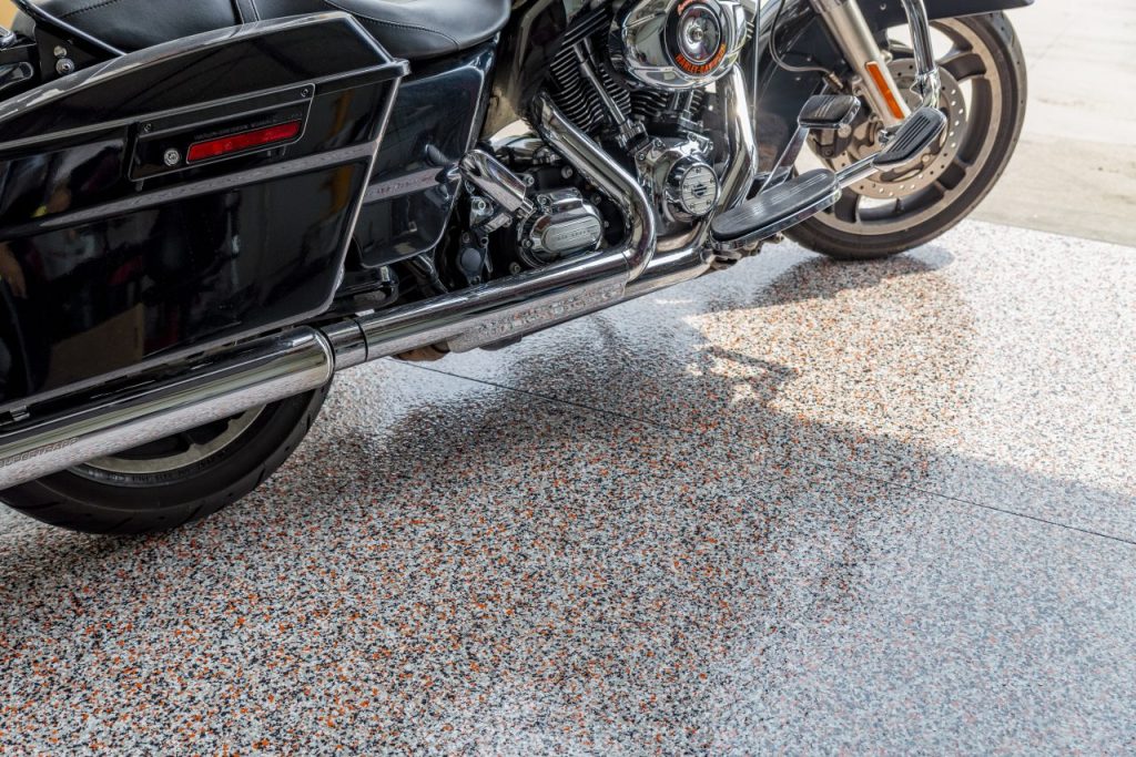 Hog garage floor coating in Twin Cities Minnesota using Torginol flake system, polyurea and polyaspartic coating with gray black white and orange Harley inspired blend